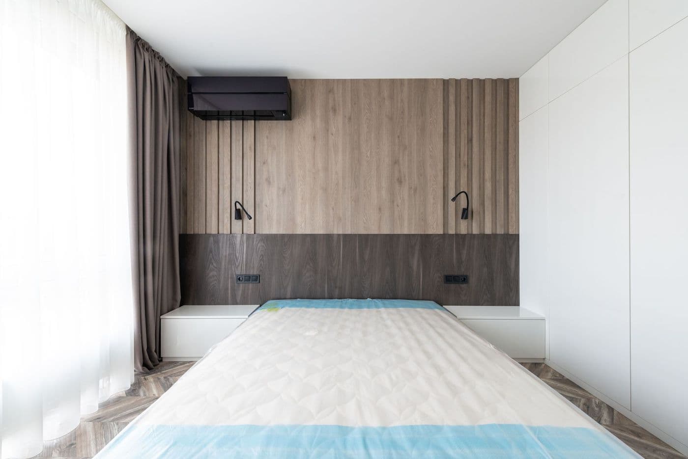 Sleek and modern bedroom featuring a minimalist design with wooden paneling and neutral tones.